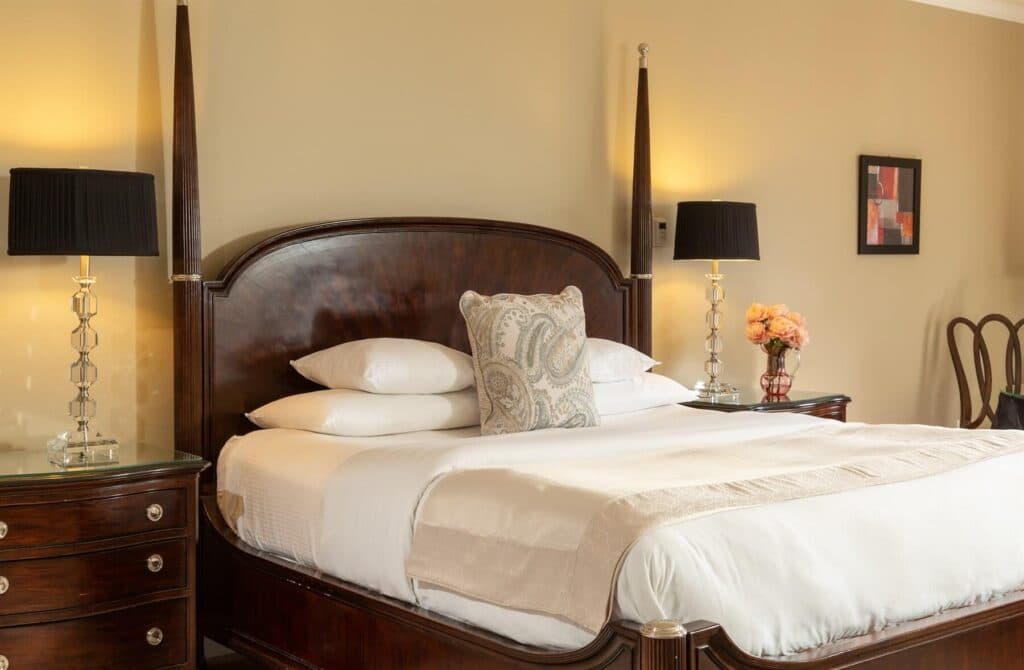 A cozy bedroom featuring a large wooden bed, decorative pillows, bedside lamps, and a vintage dresser.