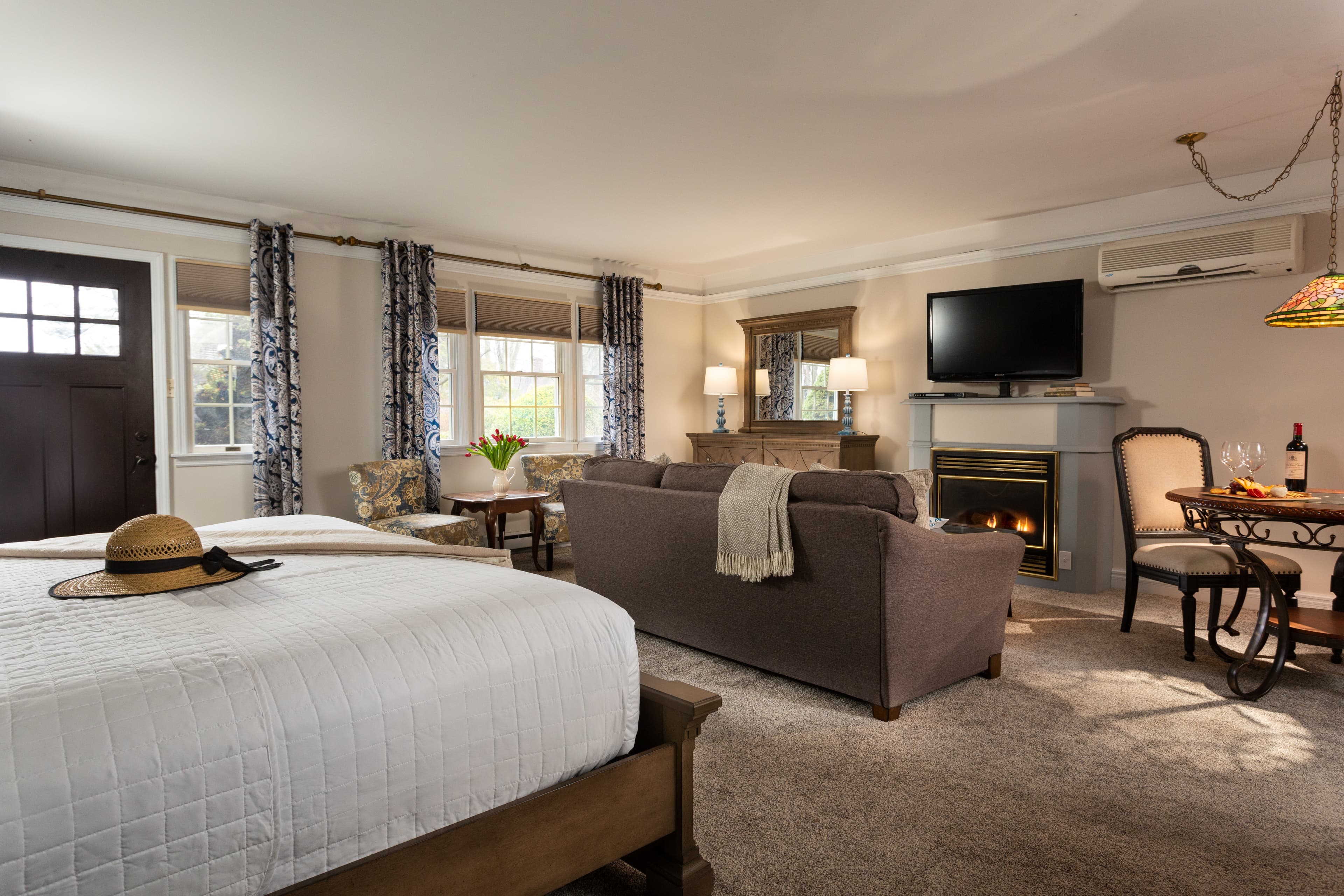 Cozy hotel room featuring a bed, seating area, fireplace, and dining table.