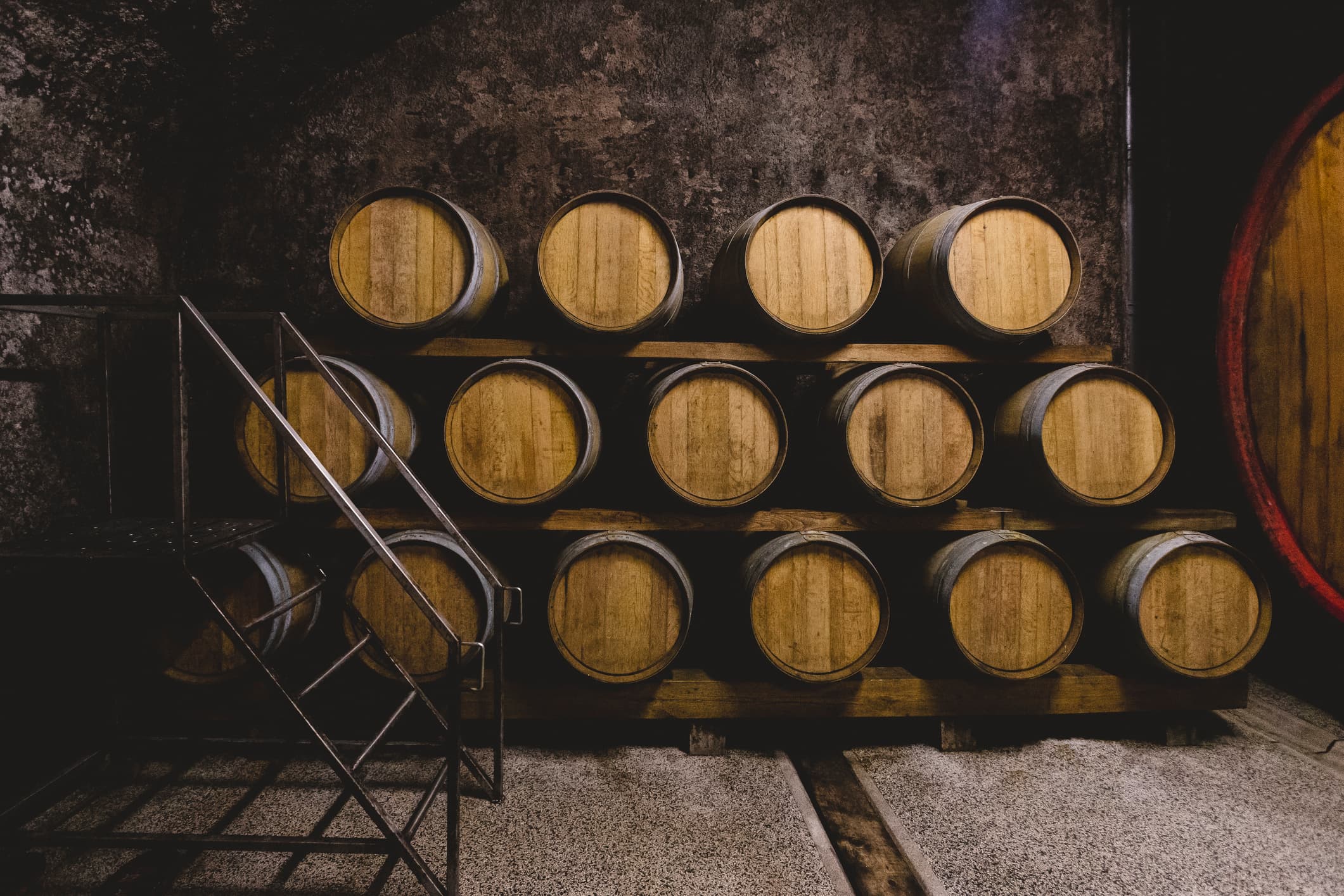 A stack of wooden barrels in a dimly lit cellar.