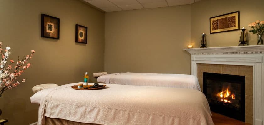 spa room within the french manor inn and spa with two massage tables by a fireplace and soft warm lighting