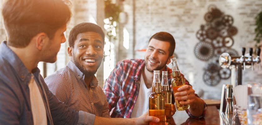 Group of men enjoying beers together at a bar while talking and smiling in a relaxed setting